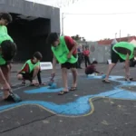 Crianças pintam rua em Campo Grande para resgatar tradição de Copa
